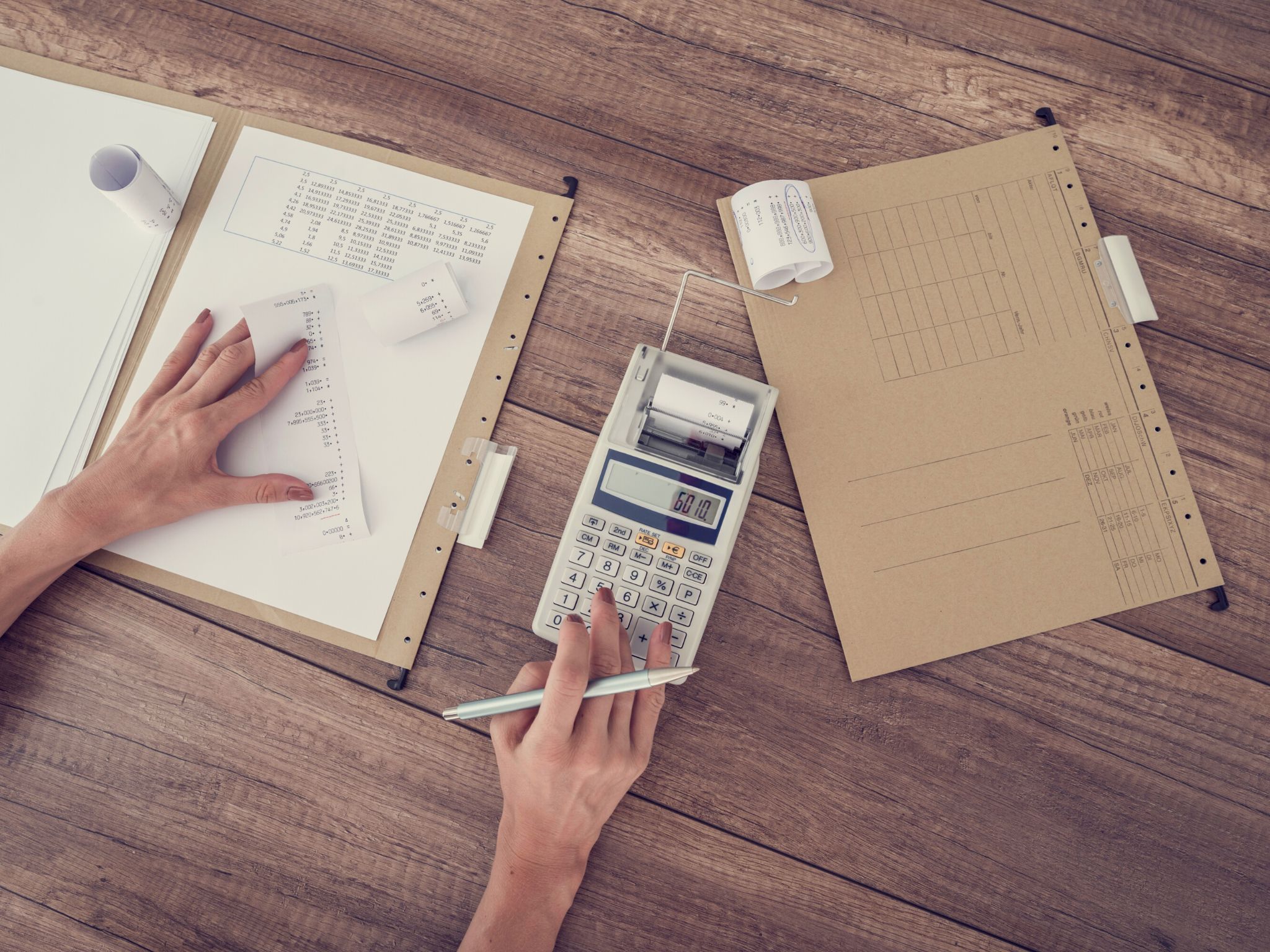 A lady at a desk working out her finances on a calculator.